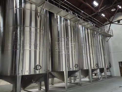 Stainless steel wine fermentation tanks lined up in a working winery