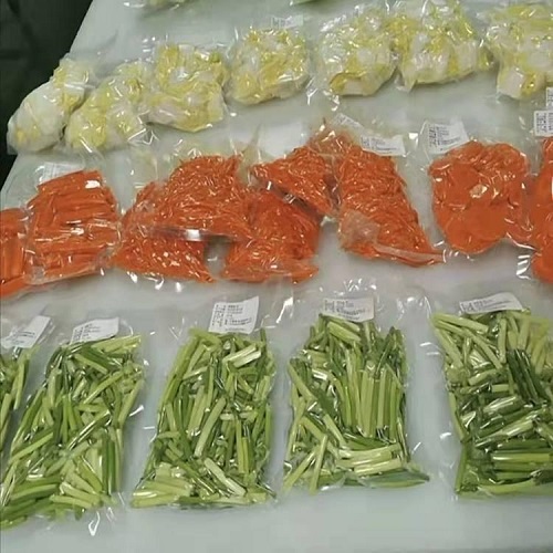 Vacuum packed meat, cheese, and vegetables on a shelf in a food processing plant