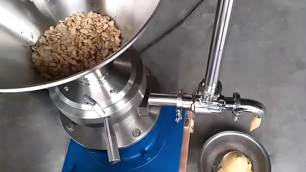 Colloid mill grinding roasted peanuts into smooth commercial peanut butter