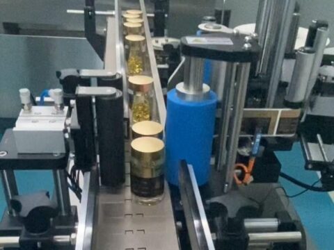 Close up of a labeling head peeling and applying a self adhesive label onto a rotating bottle