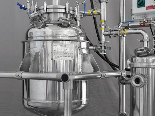 Stainless steel reactor installed in a food or beverage production line with piping and controls