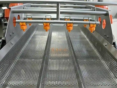 Vibration conveying mechanism and end spray on an eddy current vegetable washing machin
